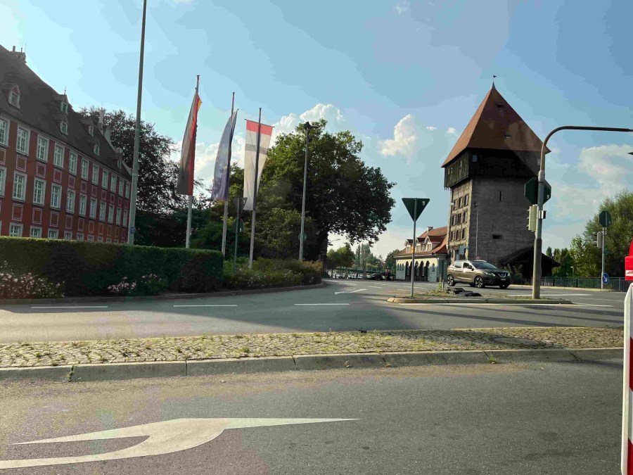 Almanya Konstanz şehrindeki tarihi Rheintorturm kulesi, önünde bayraklar ve yol görünümü.